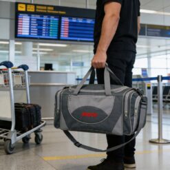 Homem em aeroporto segurando bolsa de passeio cinza ao lado do corpo