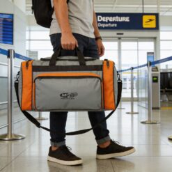 Homem segurando ao lado do corpo uma bolsa grande de aviagem zinza e laranja