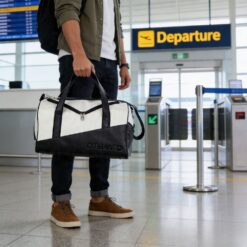 Homem segurando bolsa de viagem preta e branca na mão.