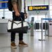 Homem segurando bolsa de viagem preta e branca na mão.