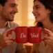 Casal olhando nos olhos enquanto brinda com uma caneca dupla com alça de coração