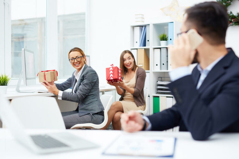Colaboradores em um escritório trocando presentes, representando o uso de brindes corporativos para valorizar e engajar a equipe no ambiente de trabalho.