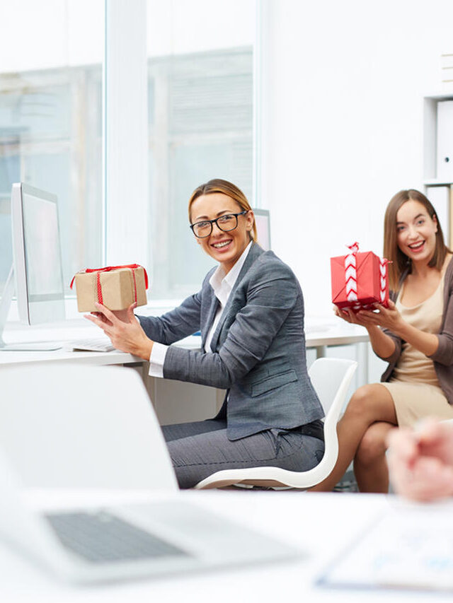 Colaboradores em um escritório trocando presentes, representando o uso de brindes corporativos para valorizar e engajar a equipe no ambiente de trabalho.