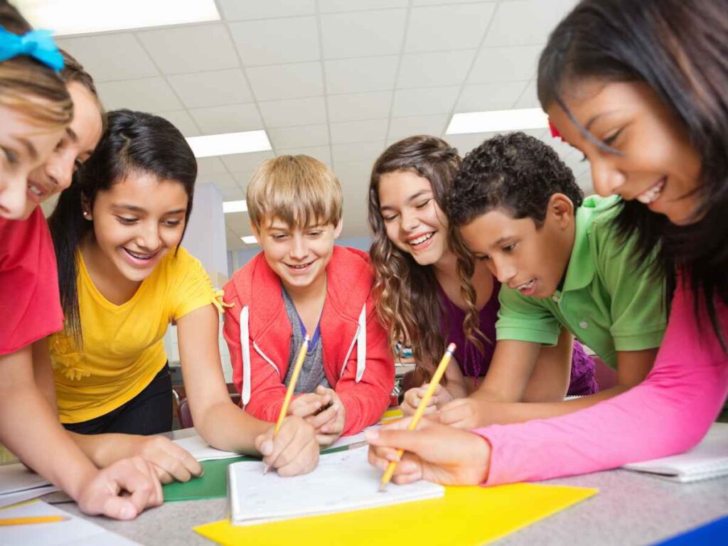 Grupo de crianças reunidas em sala de aula realizando atividade escolar colaborativa