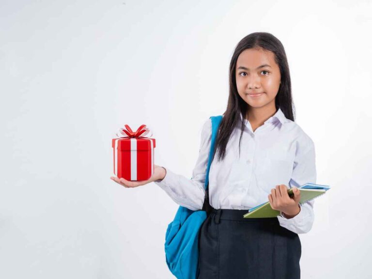 Estudante com mochila segura uma caixa de presente vermelha