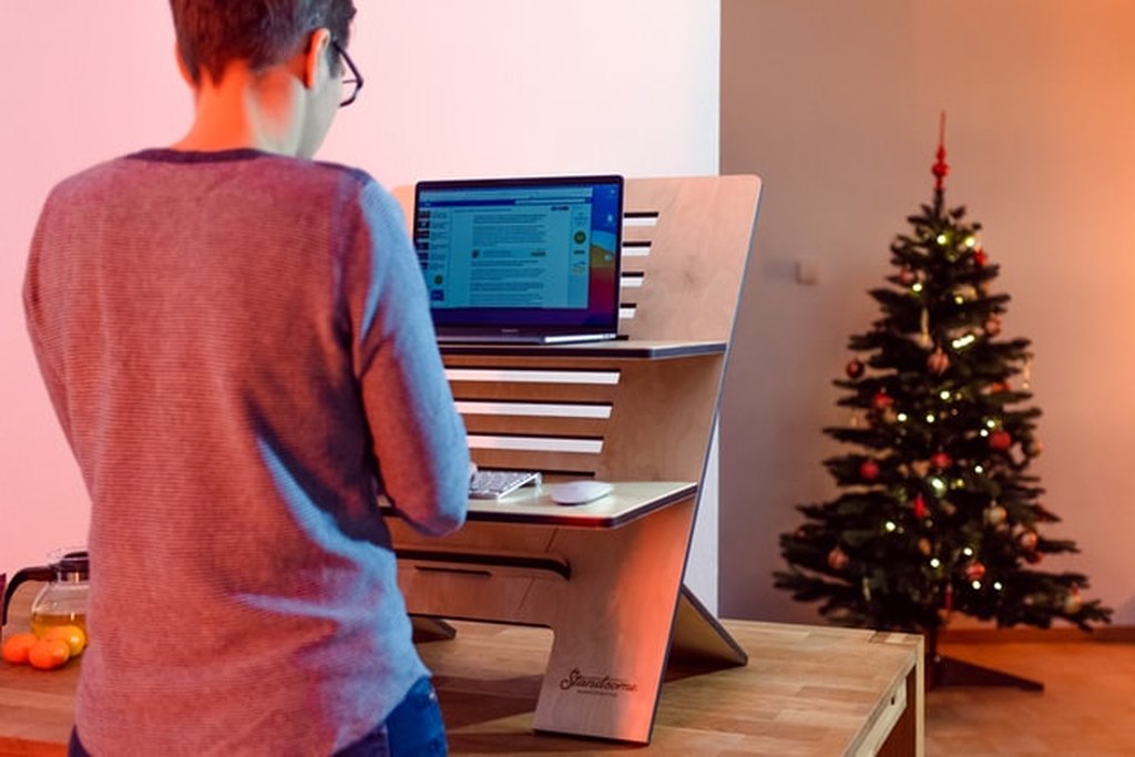 Funcionário aparece de costas trabalhando num computador. Atrás, uma árvore de natal decorada