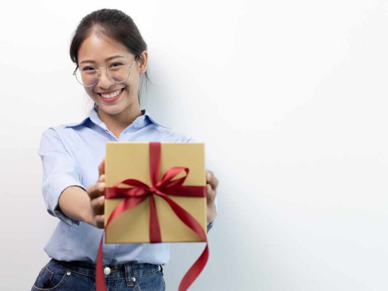 Mulher segurando brinde personalizado na frente do corpo.