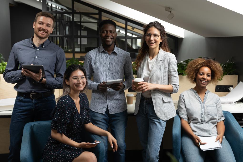 equipe de trabalho com 5 funcionários sorrindo para a câmera