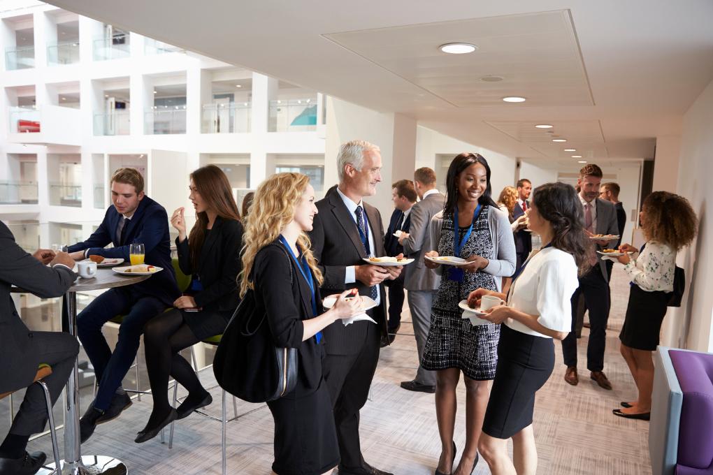 participantes de um evento corporativo em um momento de descontração, comendo e conversando