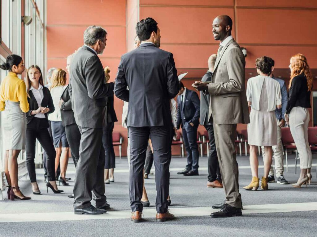 Empresa realizando evento corporativo, com todos os seus funcionários reunidos conversando e rindo.