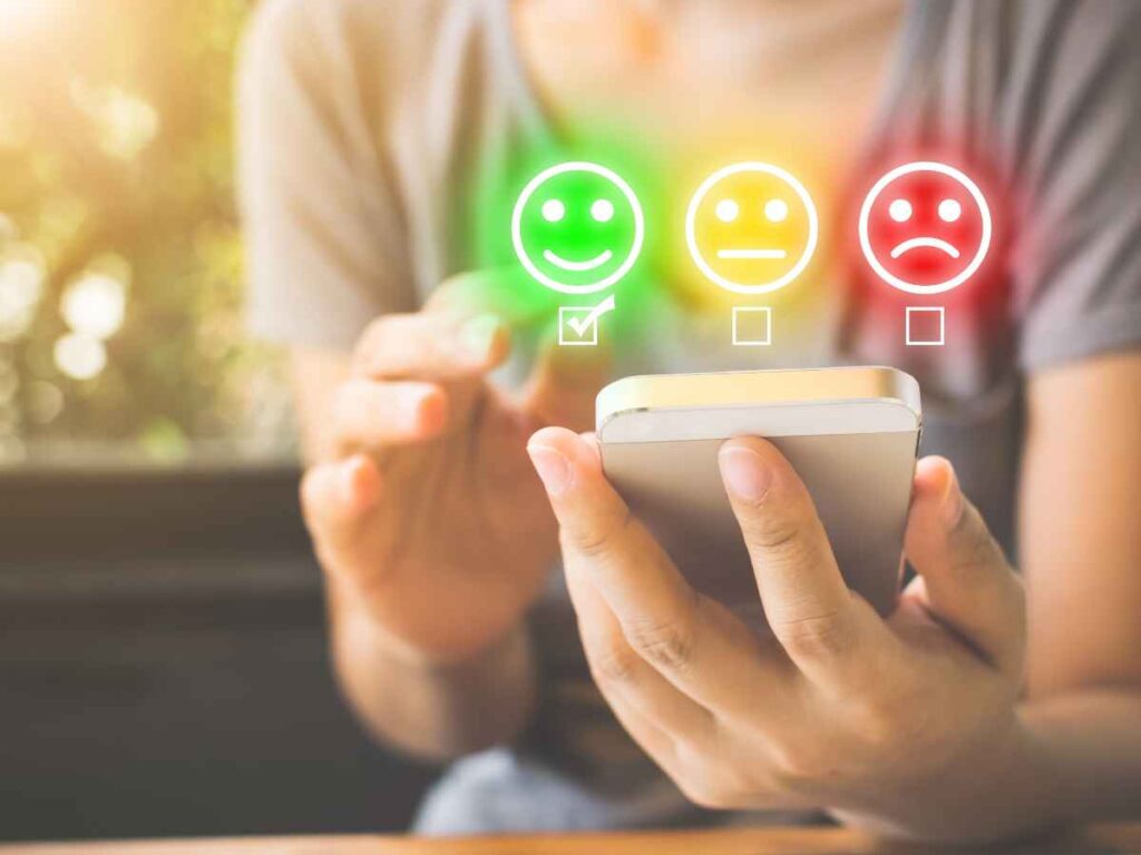 Pessoa avaliando o impacto positivo que os brindes personalizados tiveram em sua campanha de marketing. Ela segura um celular enquanto conta quantos "Satisfeitos" o público avaliou.