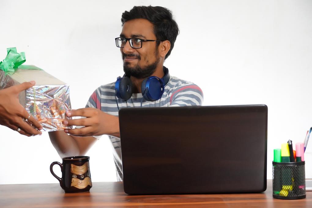 Funcionário recebendo um brinde enquanto trabalha em sua mesa com computador
