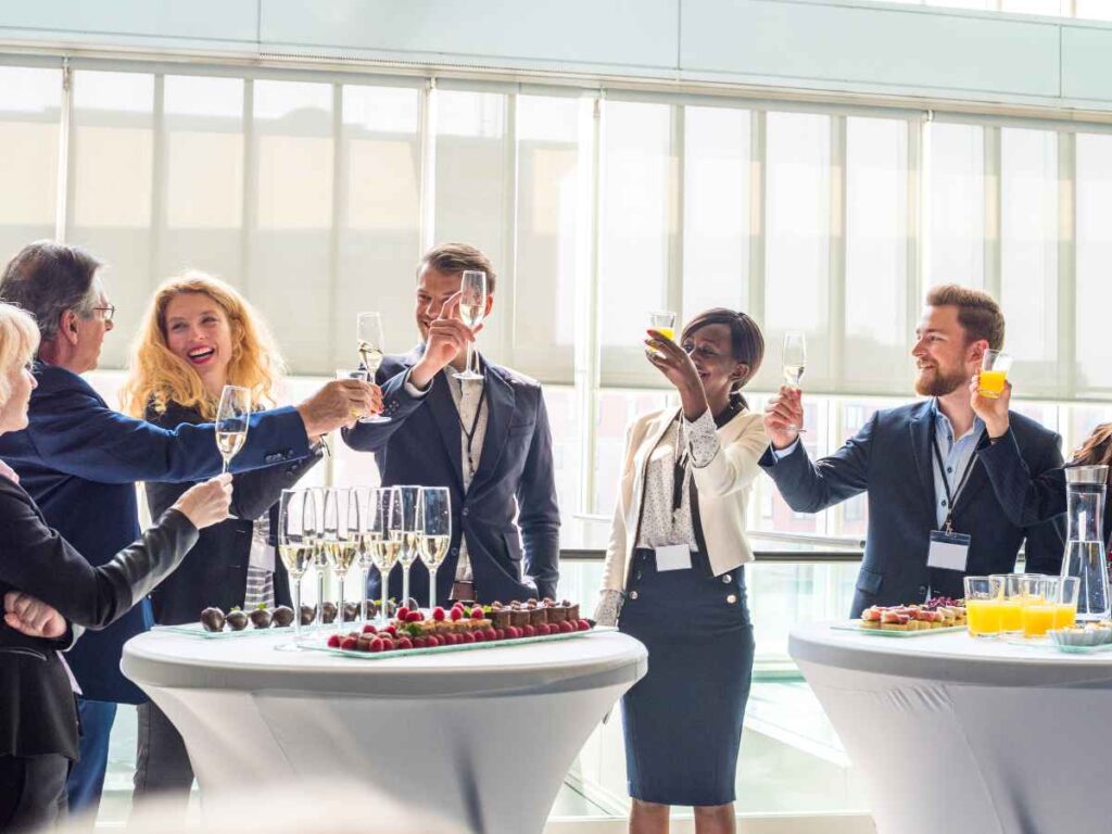 Funcionários de diversos setores interagindo em um evento corporativo, enquanto levantam um brinde.