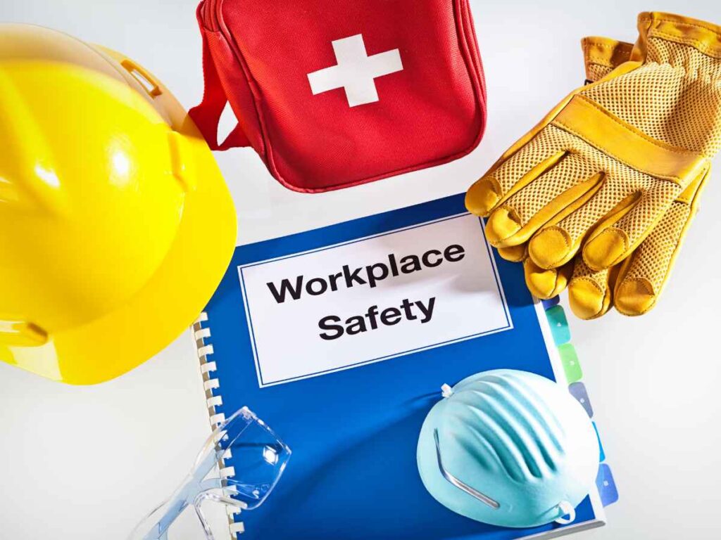 Equipamentos de proteção individual ao redor de caderno com a inscrição "Workplace Safety", representando um guia sobre a importância da cultura de segurança.