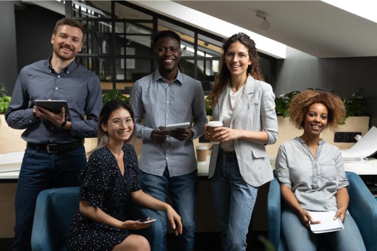 equipe de trabalho com 5 funcionários sorrindo para a câmera.