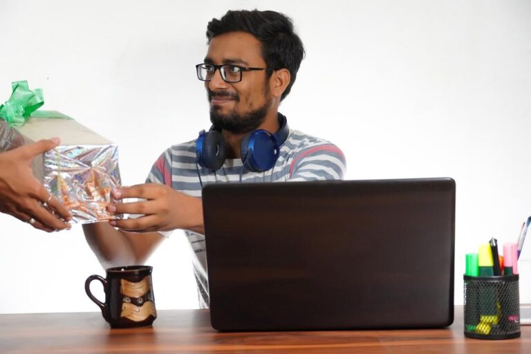Funcionário recebendo um brinde enquanto trabalha em sua mesa com computador.