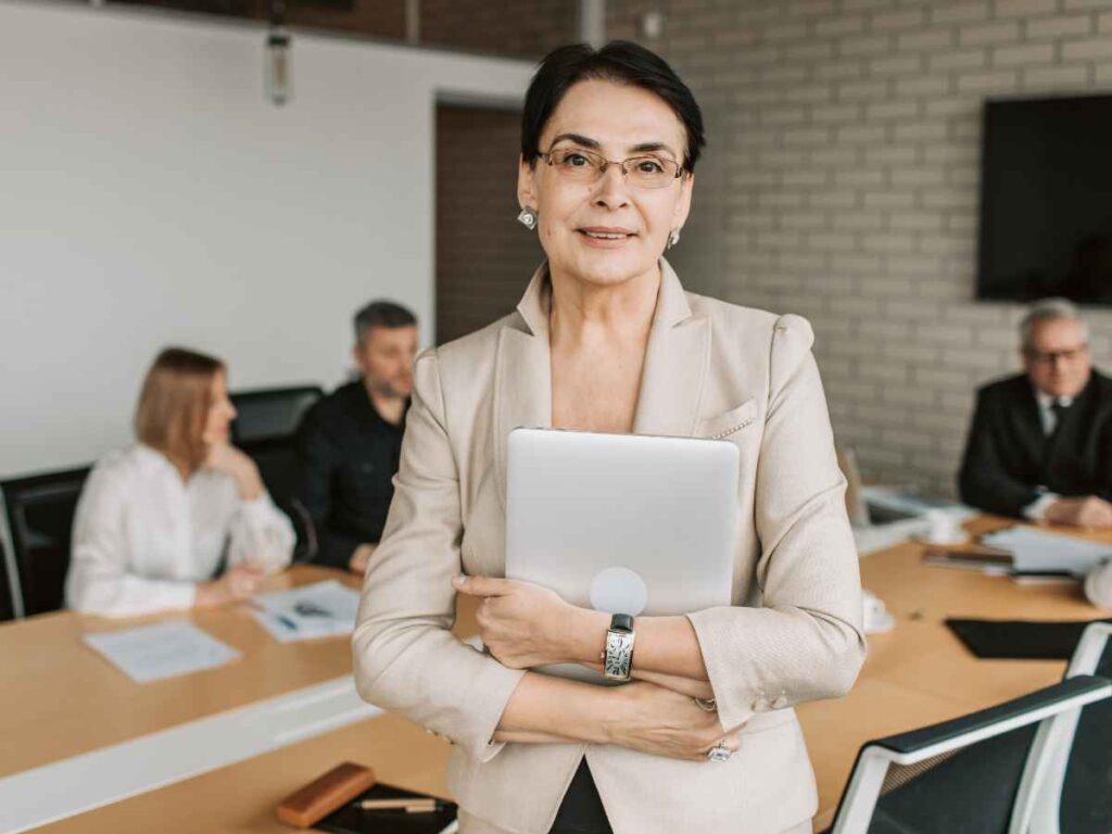 Executiva experiente segurando um tablet enquanto lidera uma reunião corporativa