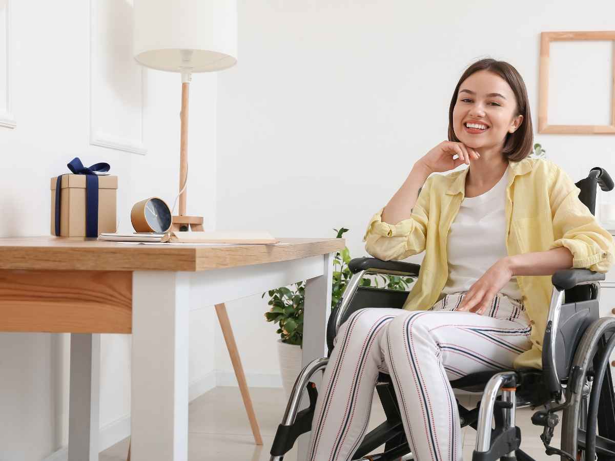 mulher em cadeira de rodas sorrindo ao lado de mesa organizada com presente decorado