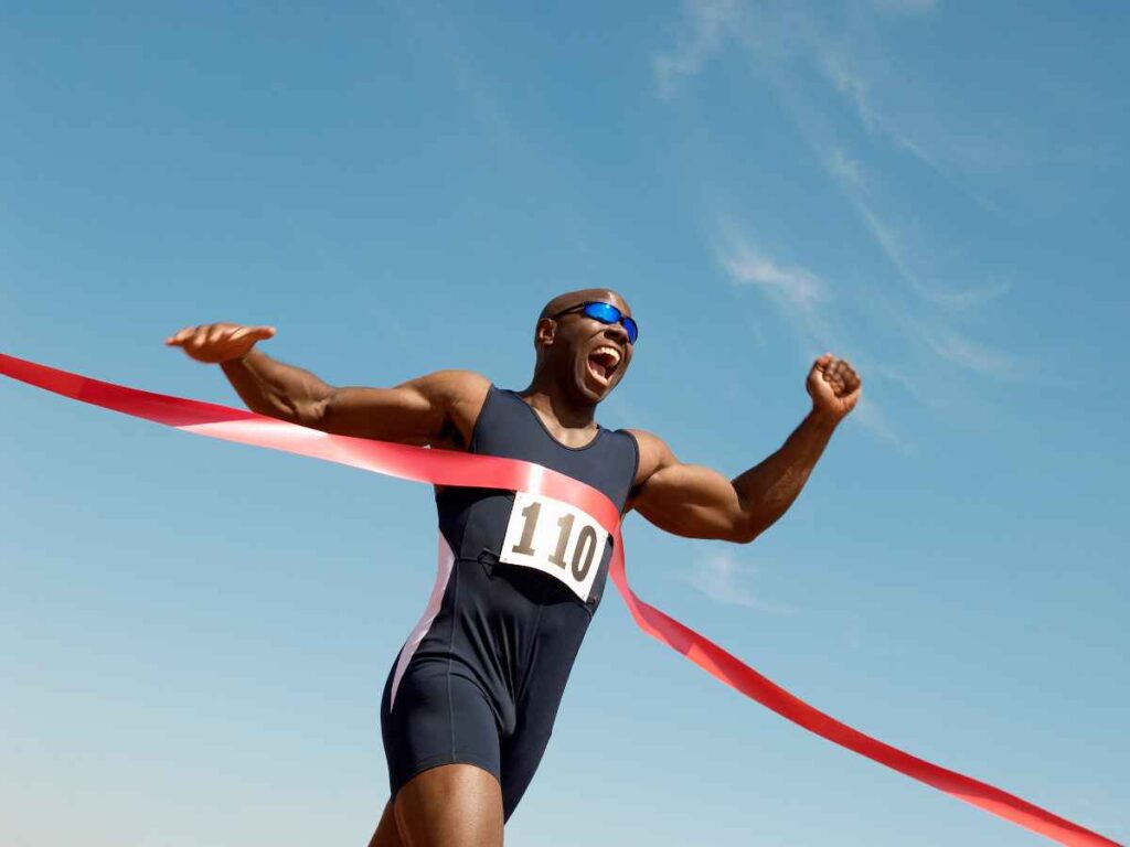 Atleta comemorando ao cruzar a linha de chegada de uma corrida