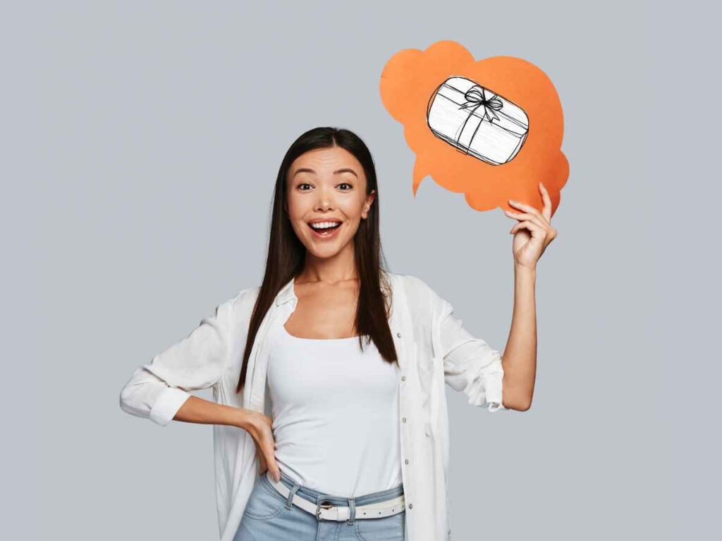Mulher sorridente segurando um balão de pensamento com desenho de presente