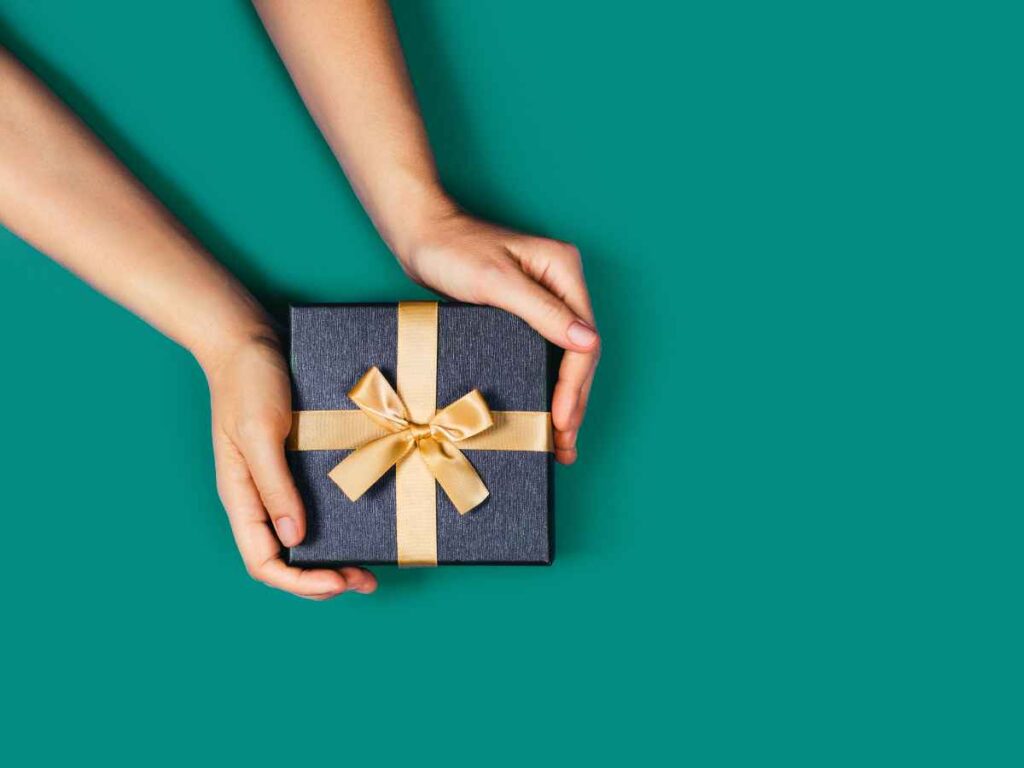 Mãos segurando uma caixa de presente embrulhada com laço