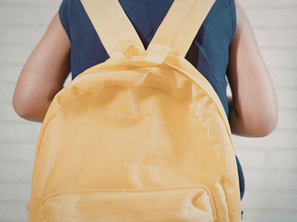 Pessoa vista de costas usando mochila amarela