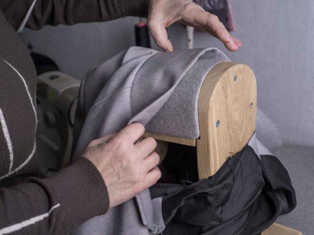 Pessoa ajustando tecido de mochila em máquina de costura durante processo de fabricação.