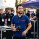 Colaborador da ESPN em evento, ele usa uma camisa polo e segura uma camera de filmagem.