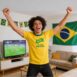 Homem comemorando gol do Brasil, ele usa uma camisa do Brasil
