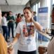 Mulher usando camiseta de poliester branca, ela conversa com algumas pessoas